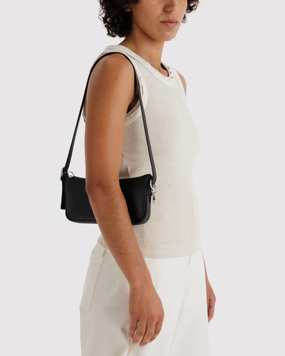 Black leather crossbody bag worn over shoulder with adjustable strap, featuring textured pebbled finish and silver hardware
