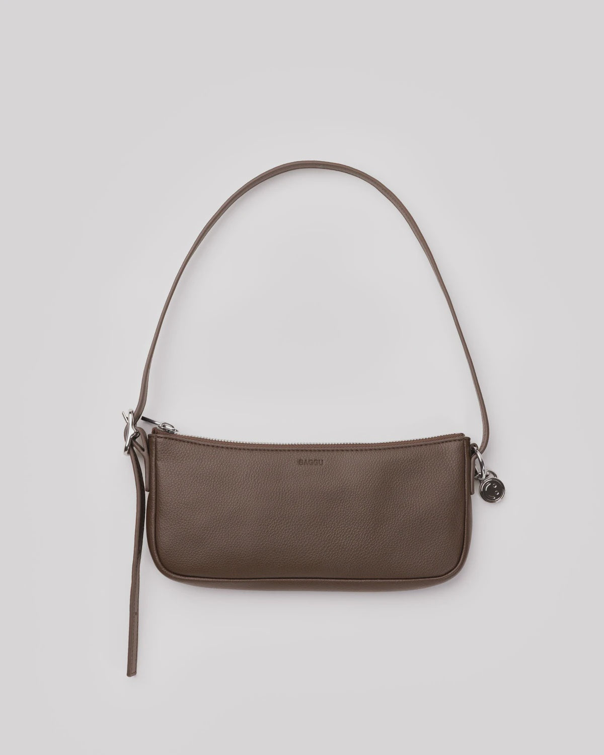 Brown leather shoulder bag with slim strap, zip closure, and silver hardware charm on neutral background