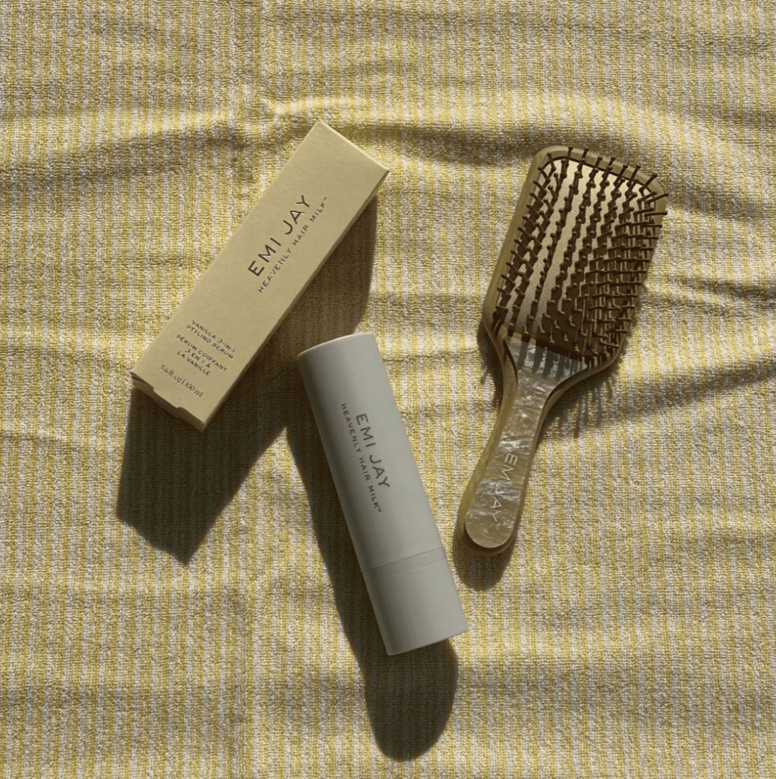 EMI JAY hairbrush and hair tie set in neutral tones on textured yellow fabric background