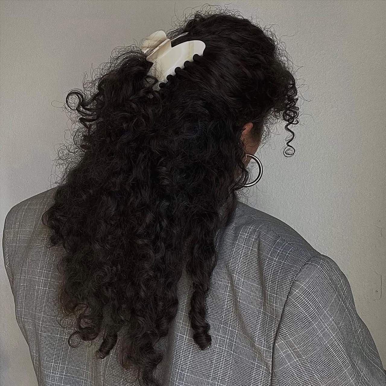 Ivory satin claw hair clip with scalloped edge detail on dark curly hair, viewed from behind
