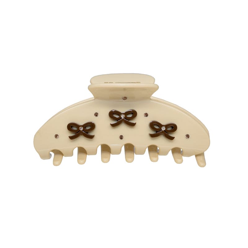 Cream-colored hair claw clip with brown bow decorations and rhinestone accents, featuring 7 teeth and a rounded top closure