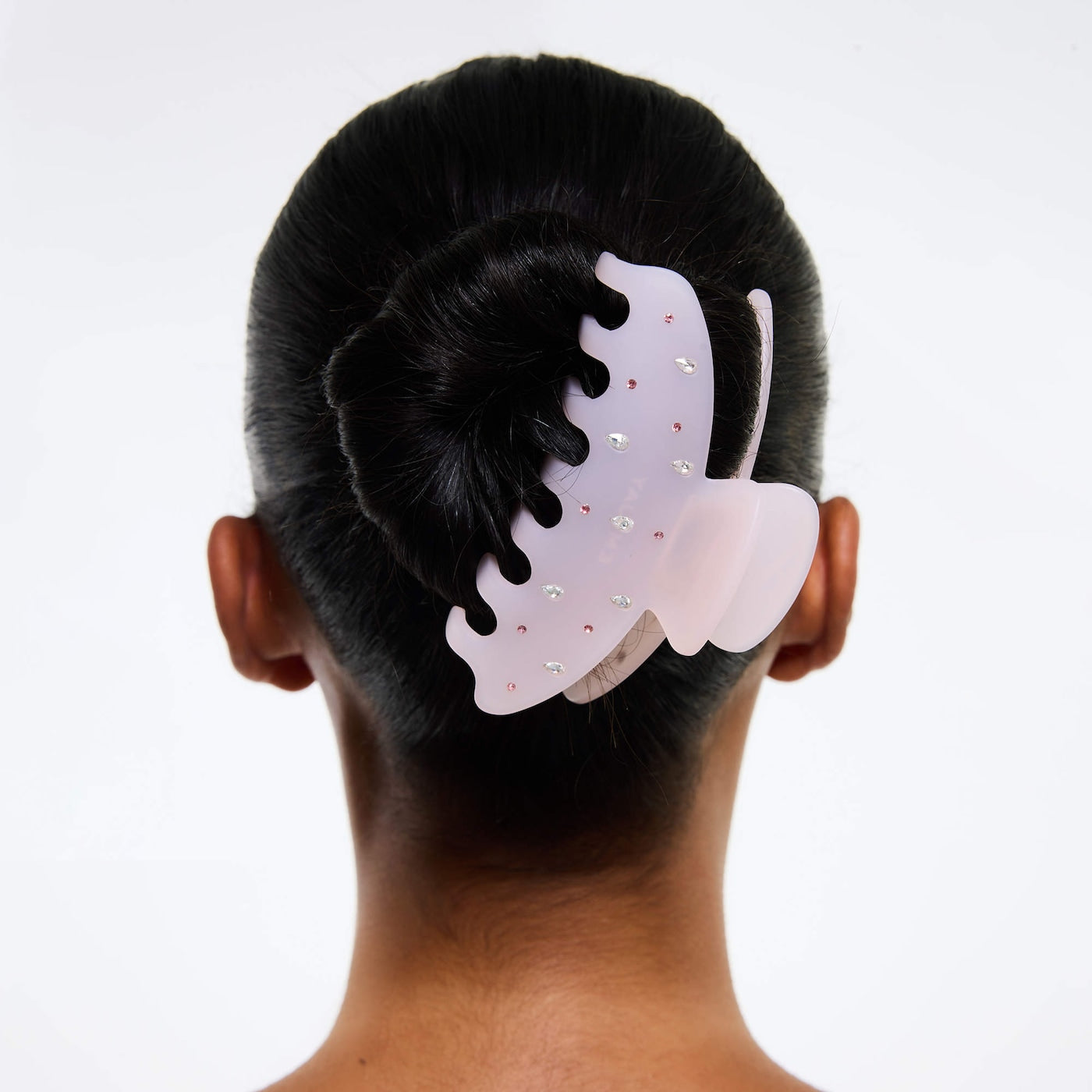 Purple butterfly-shaped hair claw clip with rhinestone embellishments and black teeth, shown securing dark hair in an updo