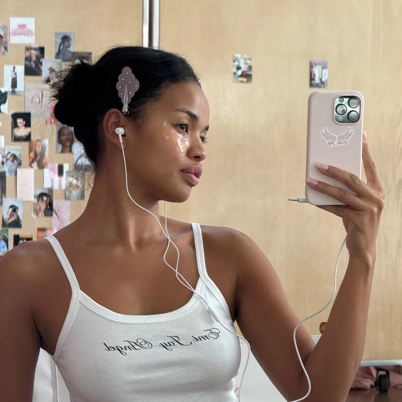 Clear butterfly-shaped hair claw clip holding back dark hair, shown in mirror selfie on person wearing white tank top
