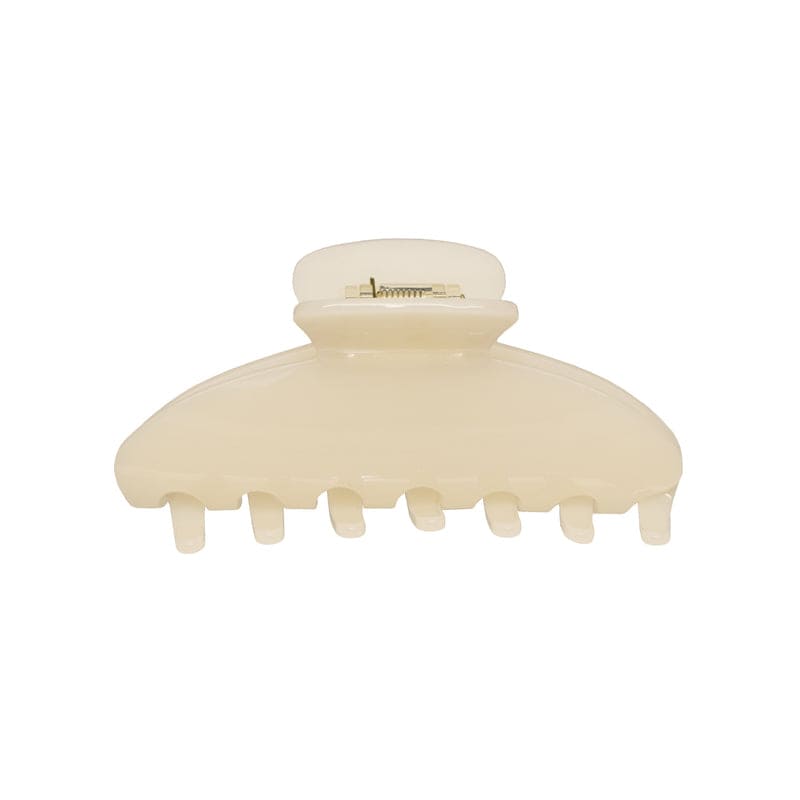 Cream-colored plastic hair claw clip with rounded shape and metal spring clasp closure, featuring seven teeth along the bottom edge