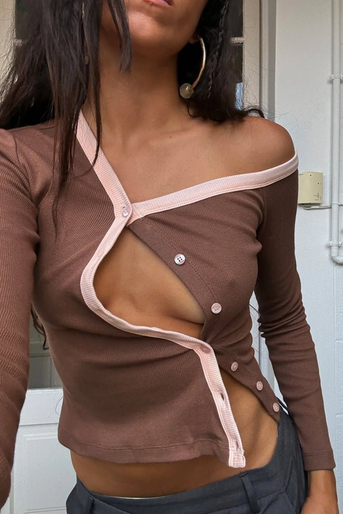 Brown ribbed cardigan with pink trim and asymmetric button closure, worn off-shoulder style