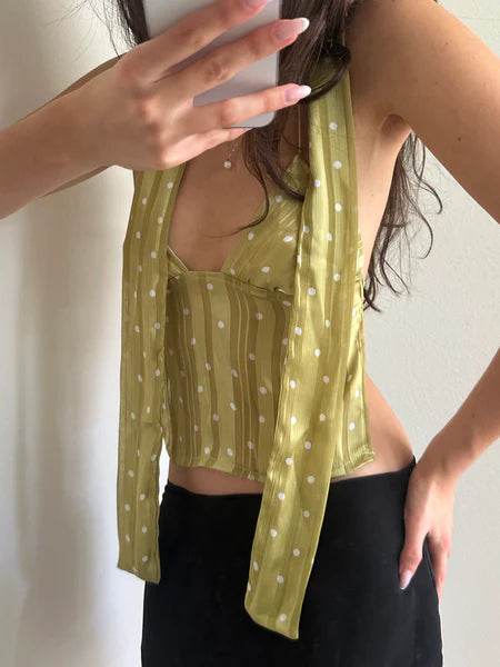 Yellow-green polka dot sleeveless crop top with attached scarf tie, worn with black pants