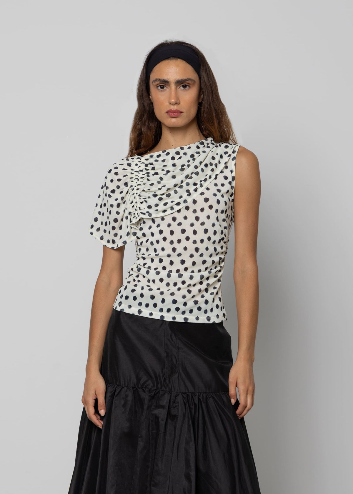 White and black polka dot asymmetric ruched top with one short sleeve and draped neckline detail.