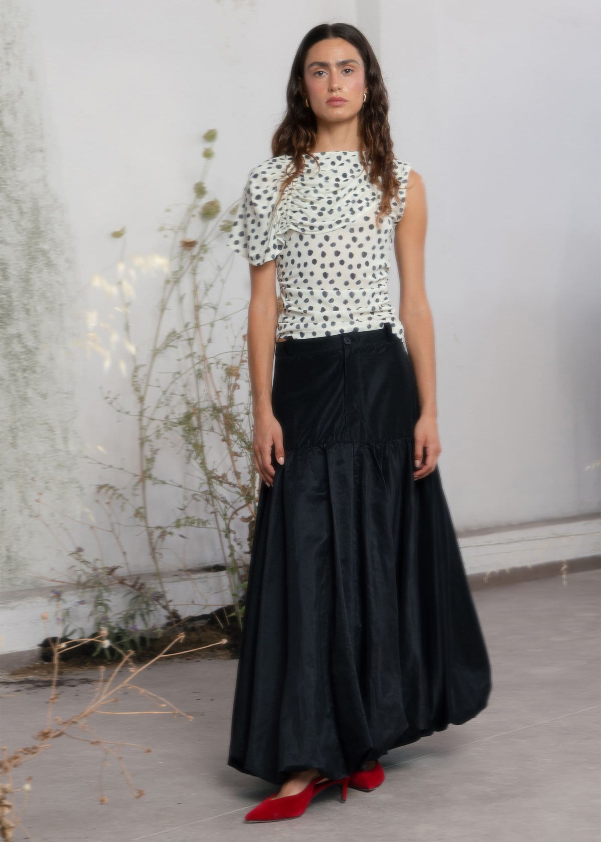 Black maxi bubble skirt with drop waist, voluminous hem, and structured upper panel, paired with red kitten heels.
