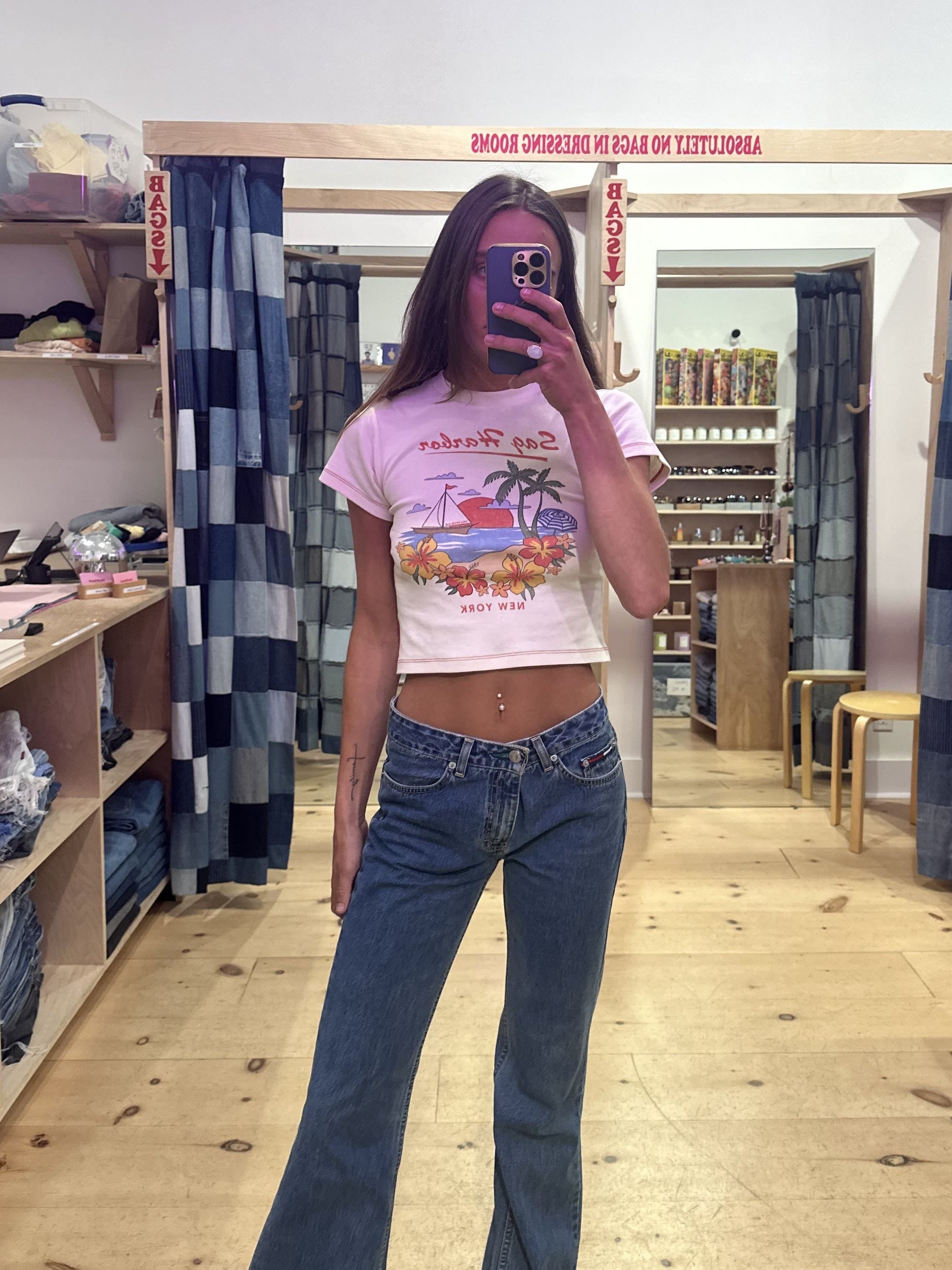 Person standing in a store with denim jeans displayed on racks.