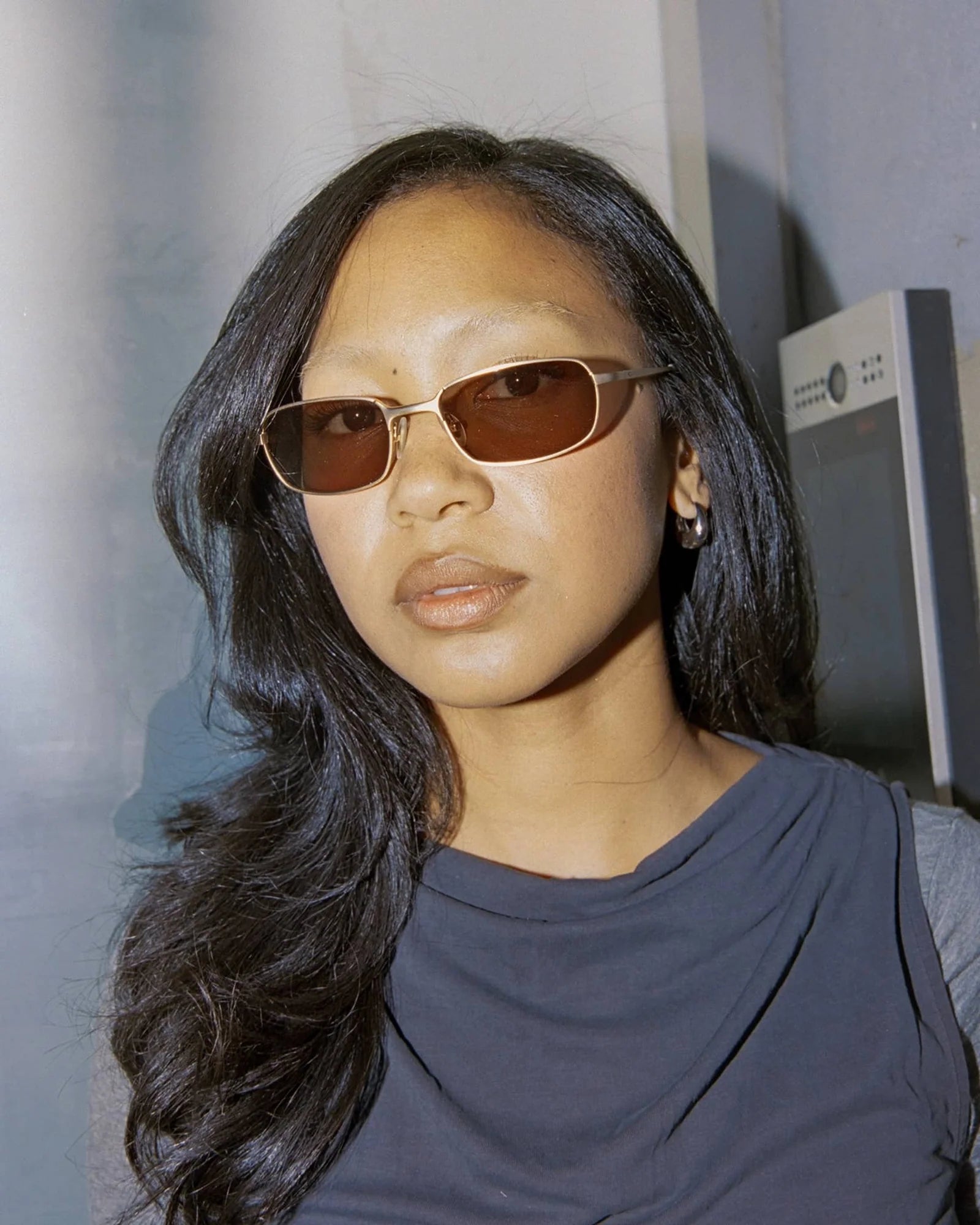 Woman wearing sunglasses and a dark top against a neutral background