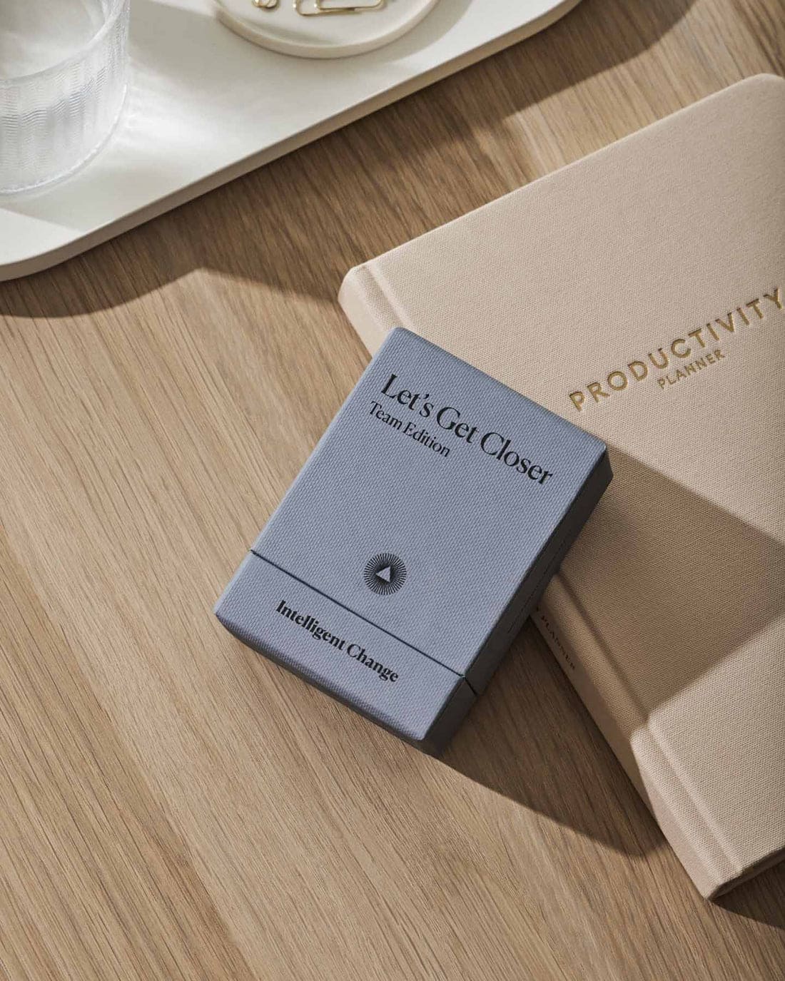 Beige and blue productivity planners on wooden desk with white tray, featuring linen-textured covers and minimalist design