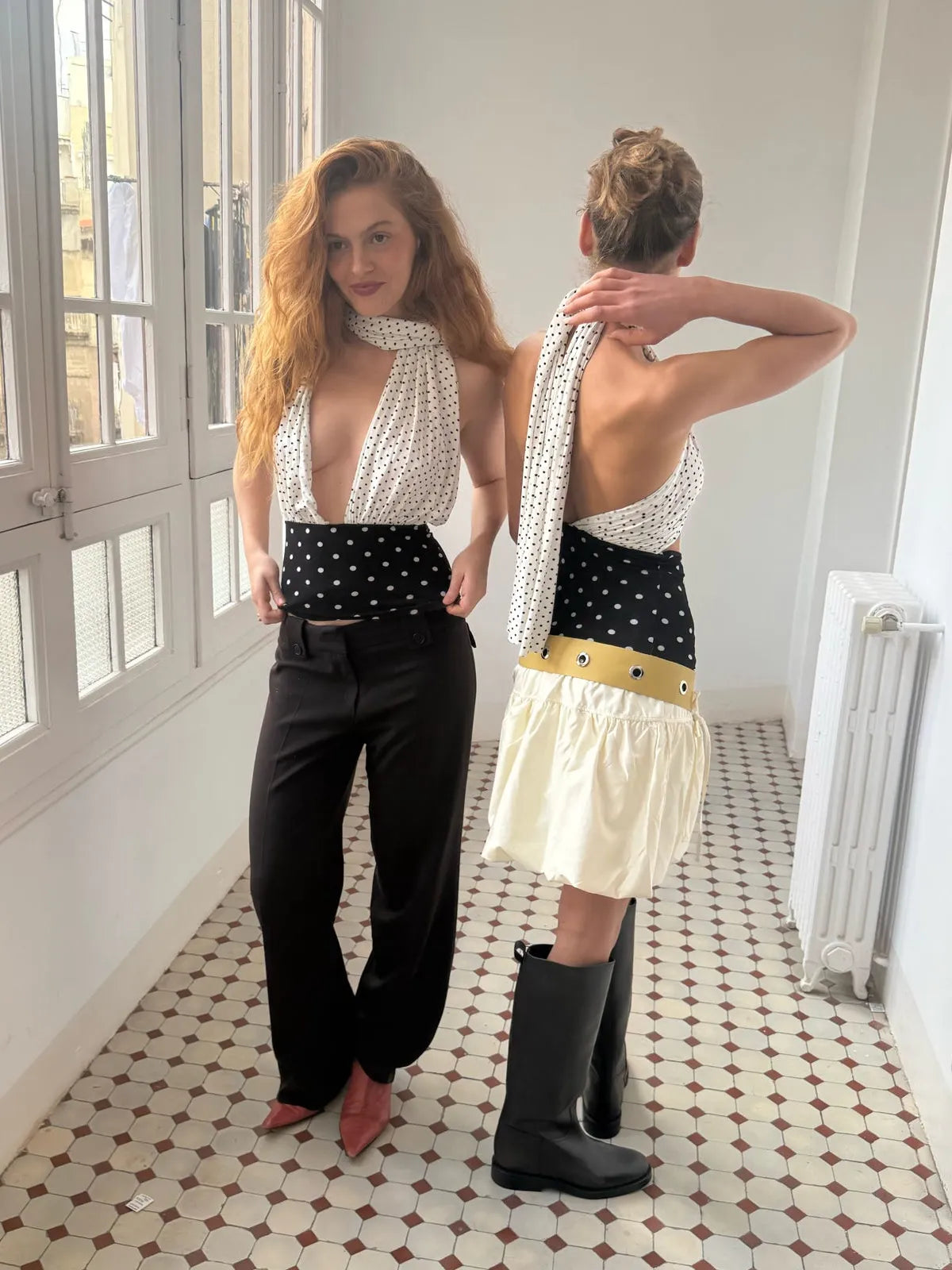 Two women wearing matching white polka dot halter tops with black polka dot waistbands, styled with different bottoms and shoes