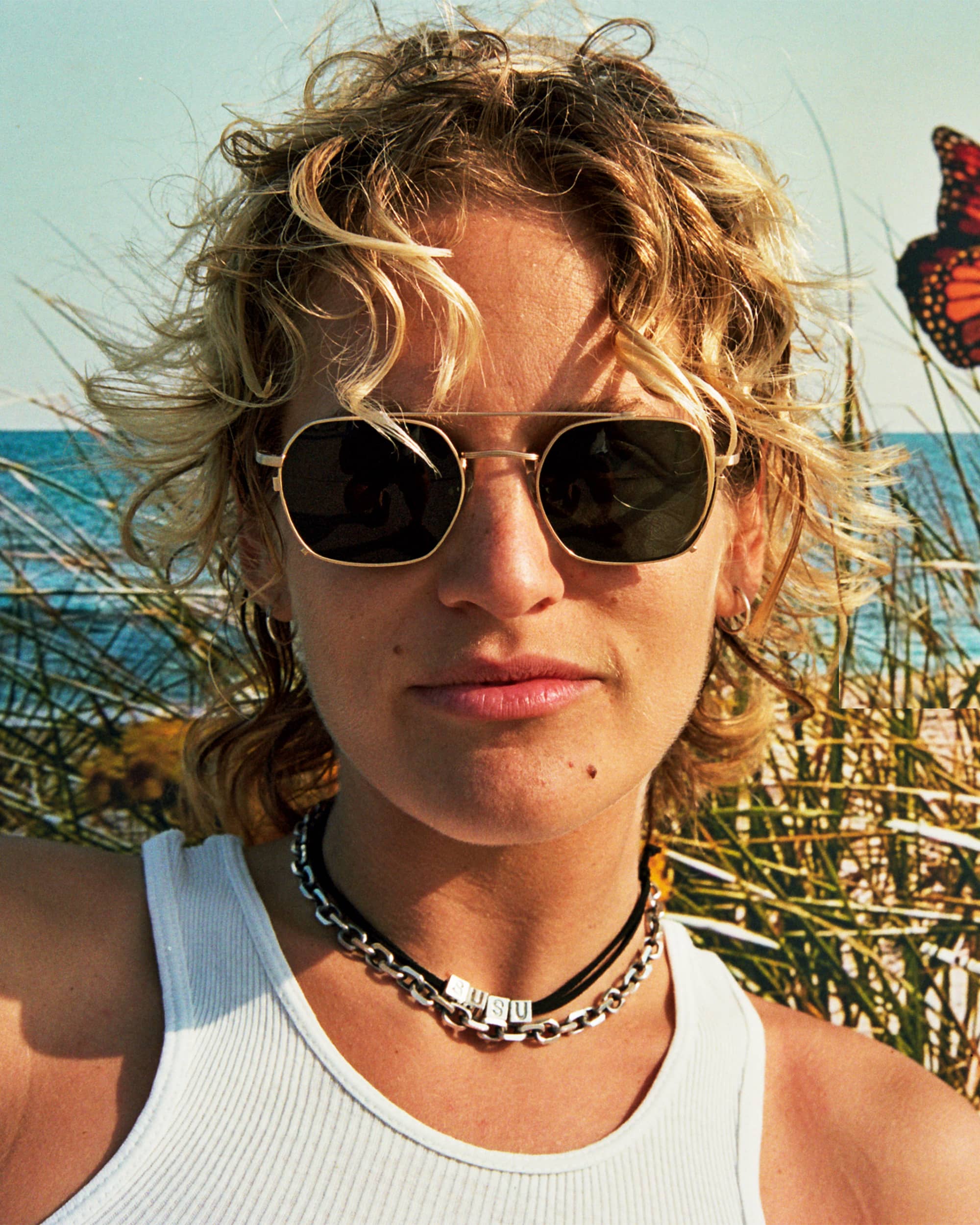 Person wearing sunglasses with a butterfly in the background