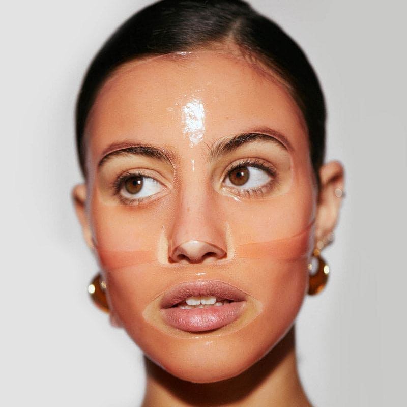 Woman demonstrating makeup contouring technique with foundation stripes on face showing color matching and blending areas