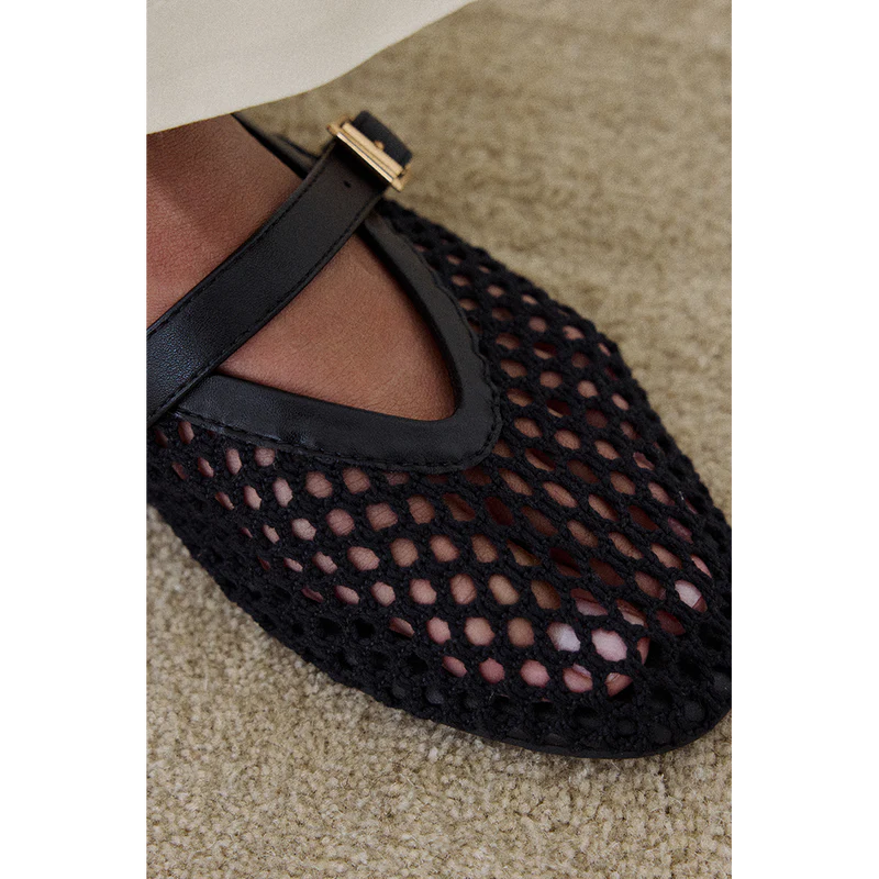 Black mesh Mary Jane flat with ankle strap and brown leather lining on beige carpet