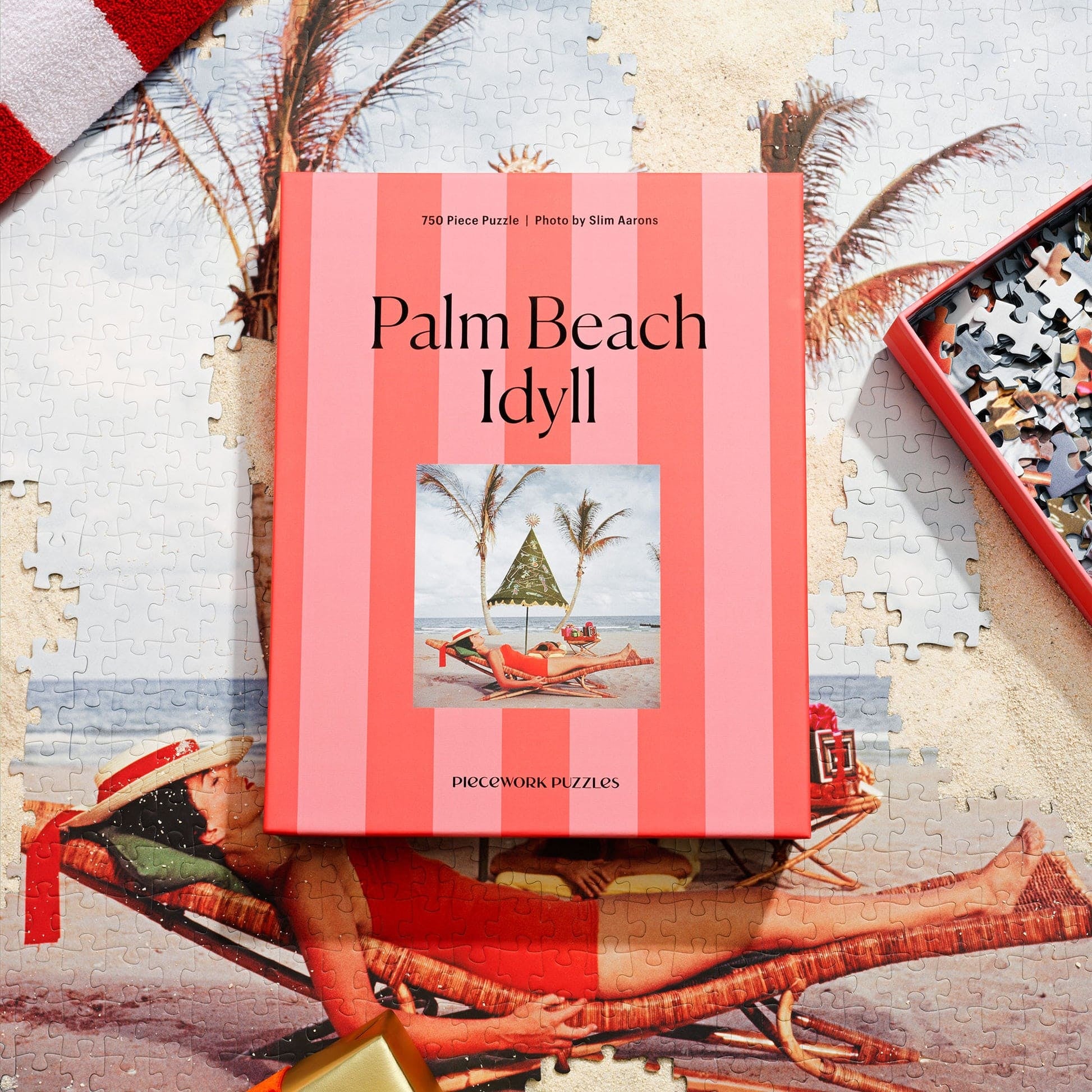 Jigsaw puzzle box featuring Palm Beach Idyll design with coral striped packaging and beach scene photo by Slim Aarons