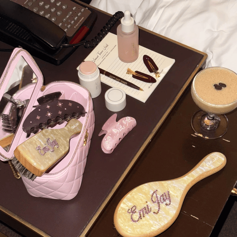 Vintage-inspired vanity set with pink quilted cosmetic bag, personalized hairbrush, beauty tools and skincare products on brown tray