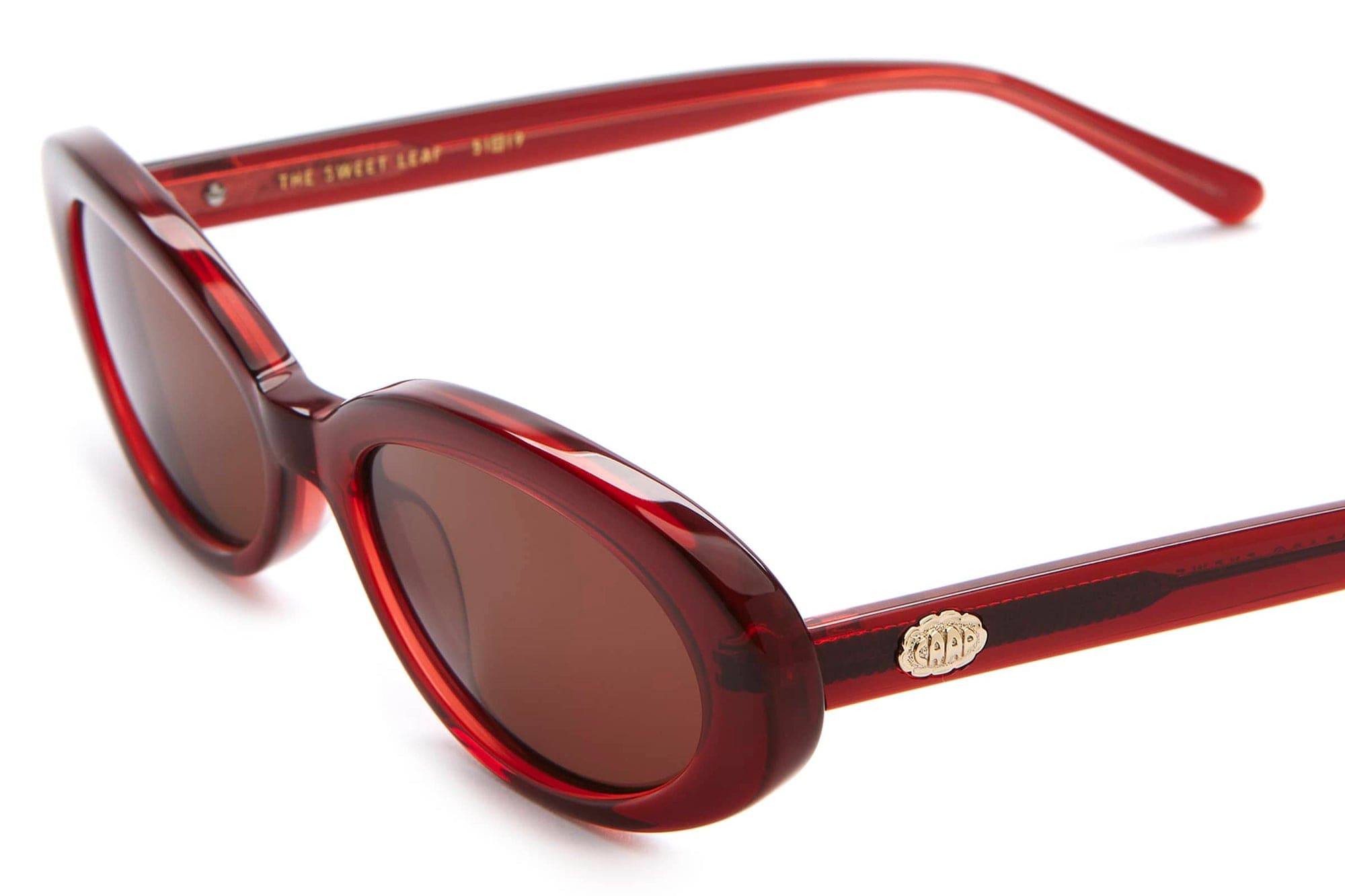 Red transparent oval sunglasses with brown lenses and gold logo detail on temple