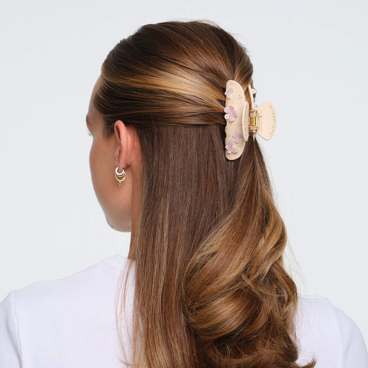 Beige hair claw clip with pink floral embellishments and gold accents securing brown highlighted hair in half-up style