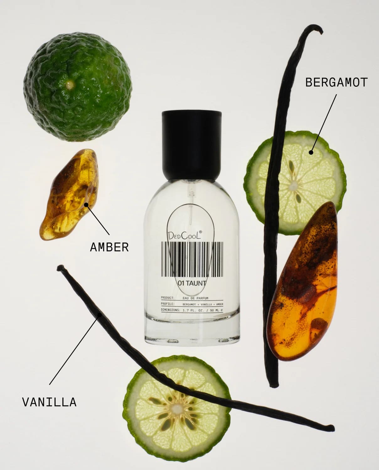 Clear glass perfume bottle with black cap surrounded by bergamot slices, amber pieces, and vanilla beans on white background