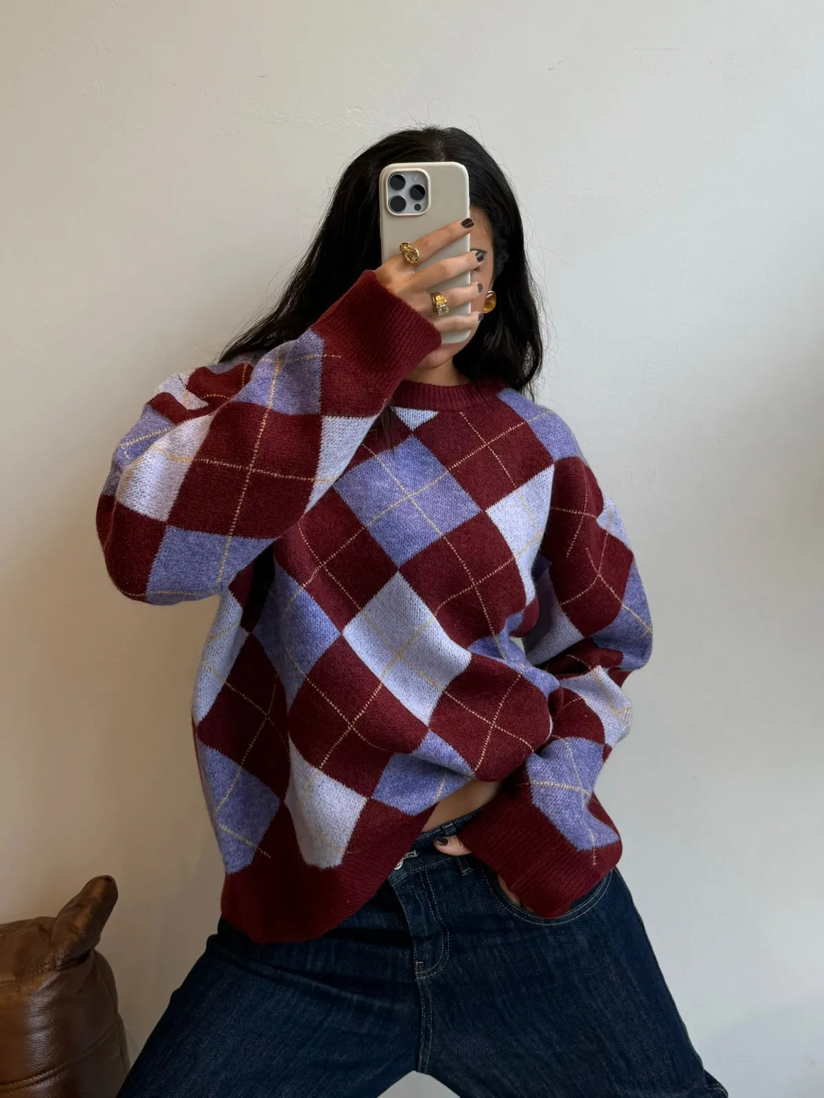 Oversized burgundy and purple argyle knit sweater with diamond pattern, worn with dark denim jeans