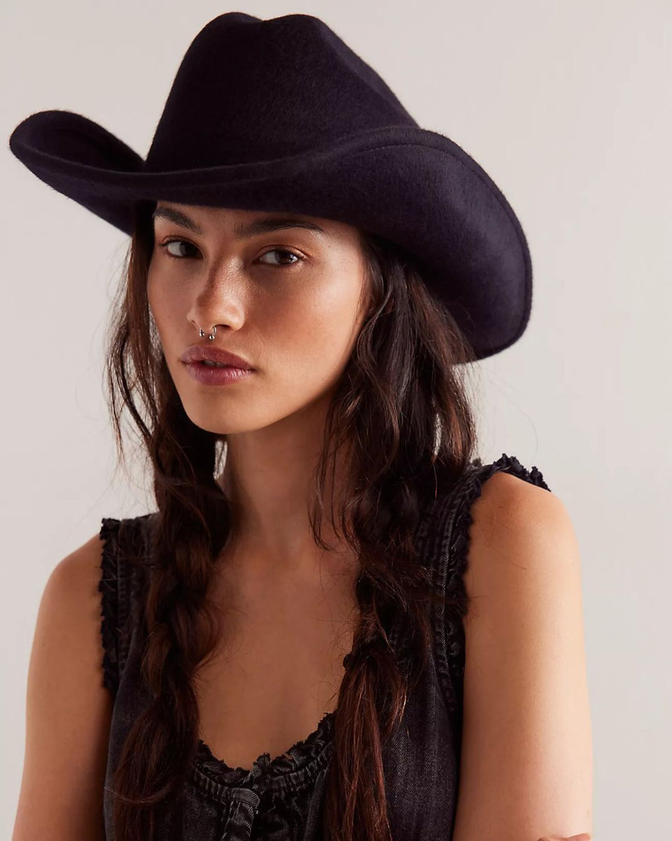 Black felt cowboy hat with wide curved brim and high crown, worn by model with long dark hair