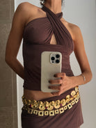 Brown halter neck ruched top with cutout detail and gold embellished coin belt at waist