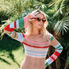 Woman wearing a colorful crochet dress with sunglasses in a garden setting