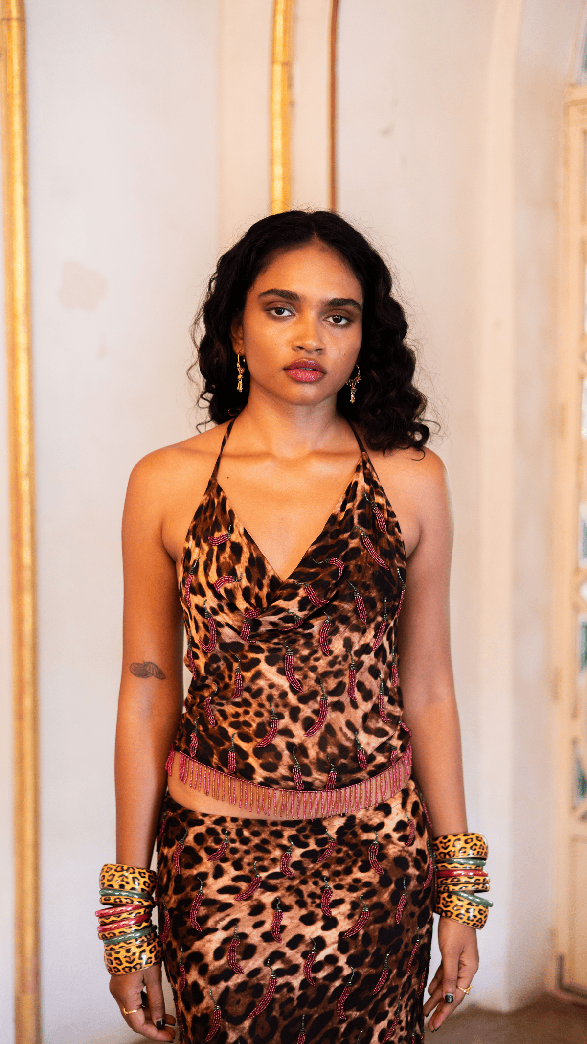 Woman wearing leopard print halter dress with beaded embellishments and matching animal print bracelets