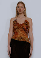 Rust-colored printed cami top with ruffled neckline and thin straps, paired with black skirt