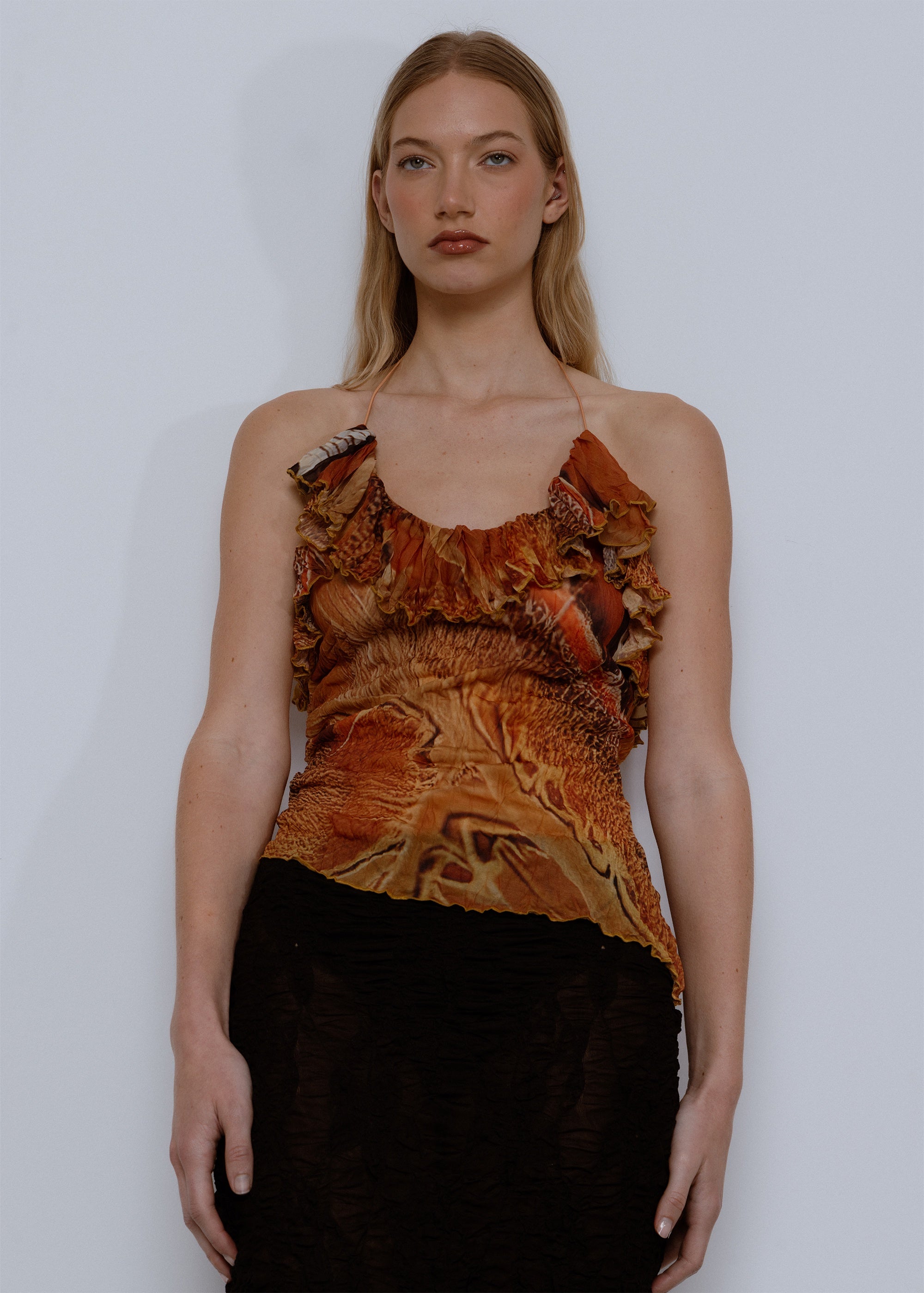 Rust-colored printed cami top with ruffled neckline and thin straps, paired with black skirt