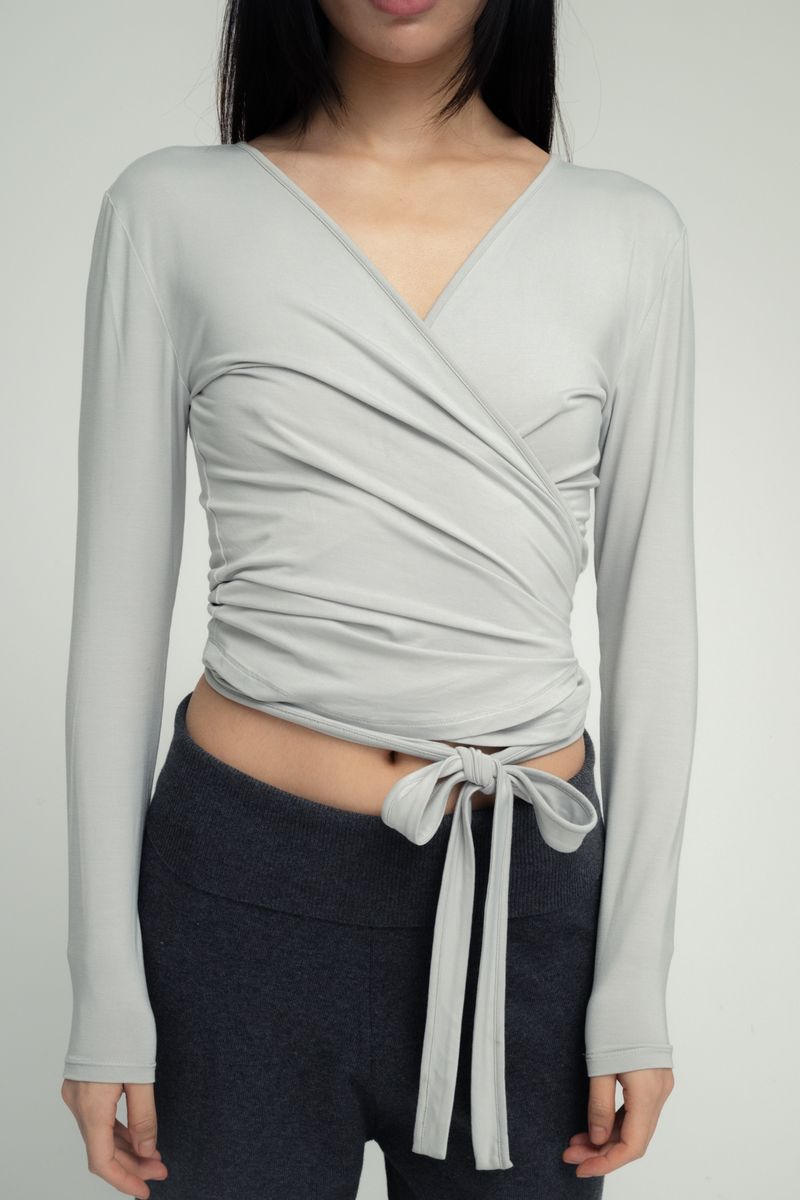 Light gray long-sleeve wrap top with tie waist closure and V-neckline in soft stretchy fabric
