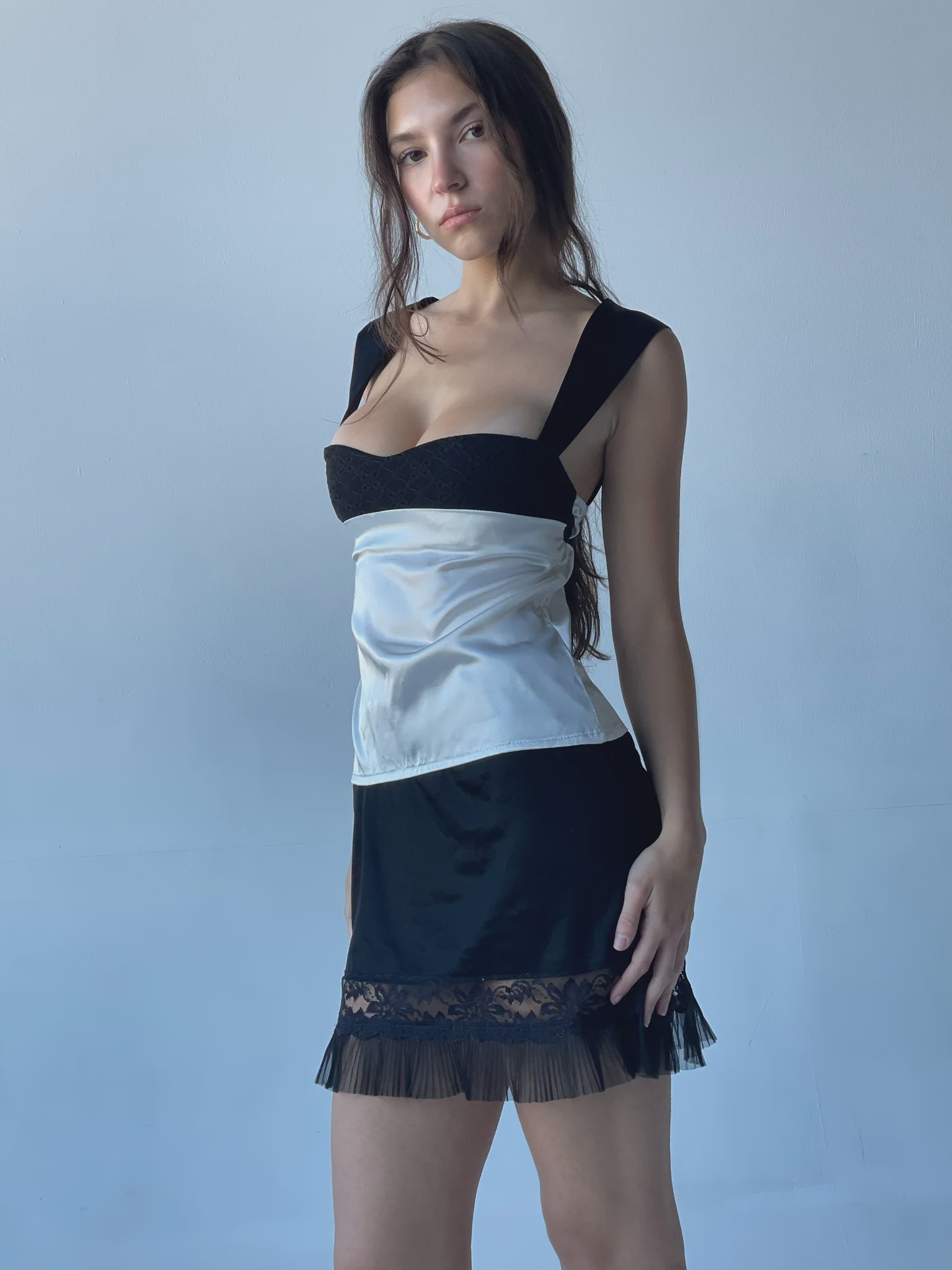 Woman wearing a black and white dress with sheer overlay against a plain background