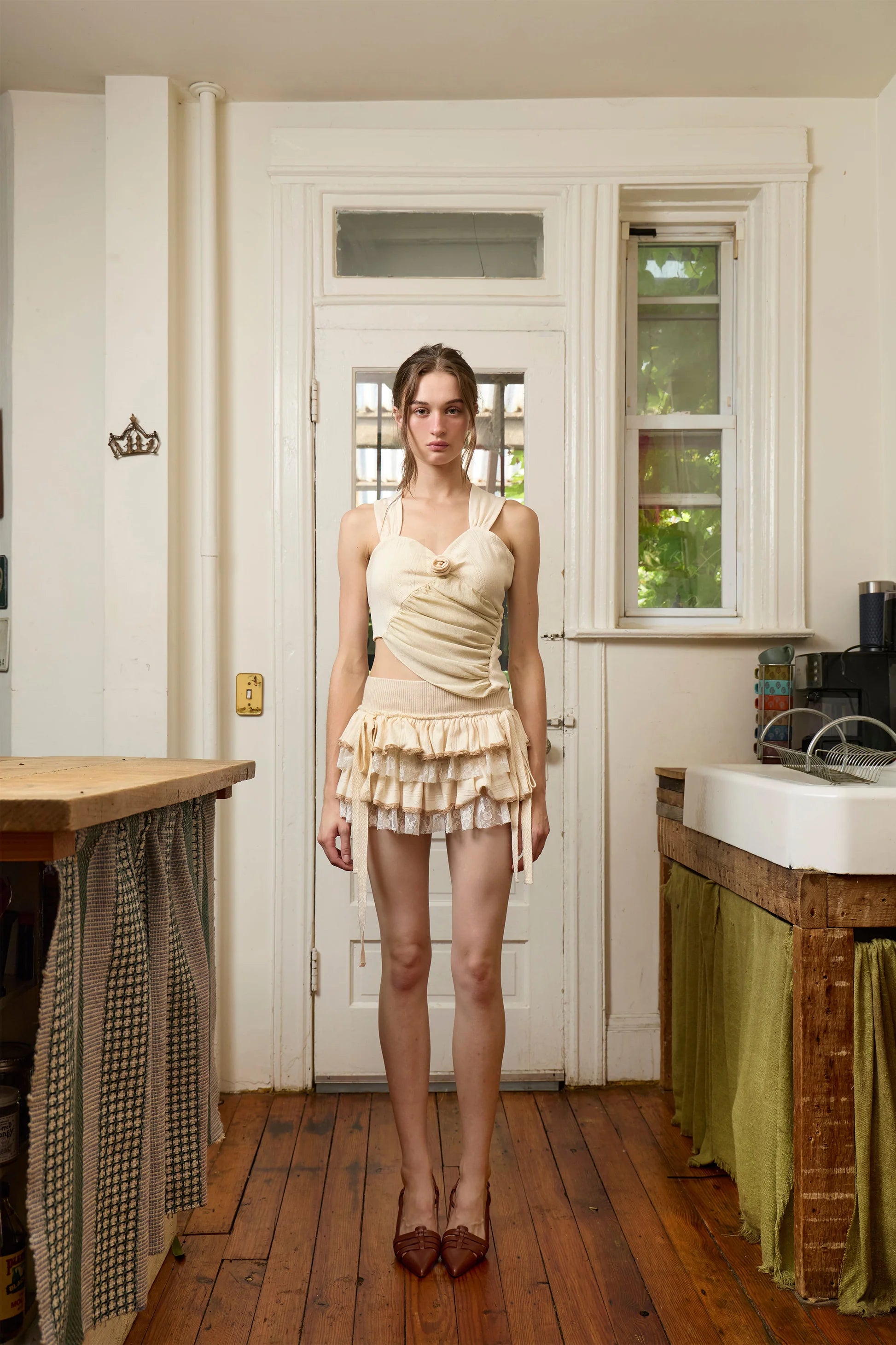 Cream sleeveless wrap top with tiered ruffle mini skirt set in soft neutral tones, featuring asymmetric draping and lace details