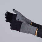 Two-tone knit gloves in gray and black with ribbed cuffs, shown on hands against gray background