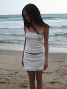 White ribbed cotton camisole and skirt set with lace trim details, worn on beach