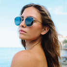 Woman wearing sunglasses with a blurred beach background