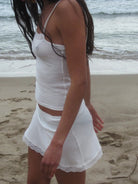 White ribbed knit two-piece beach set with camisole top and mini skirt with lace trim detail
