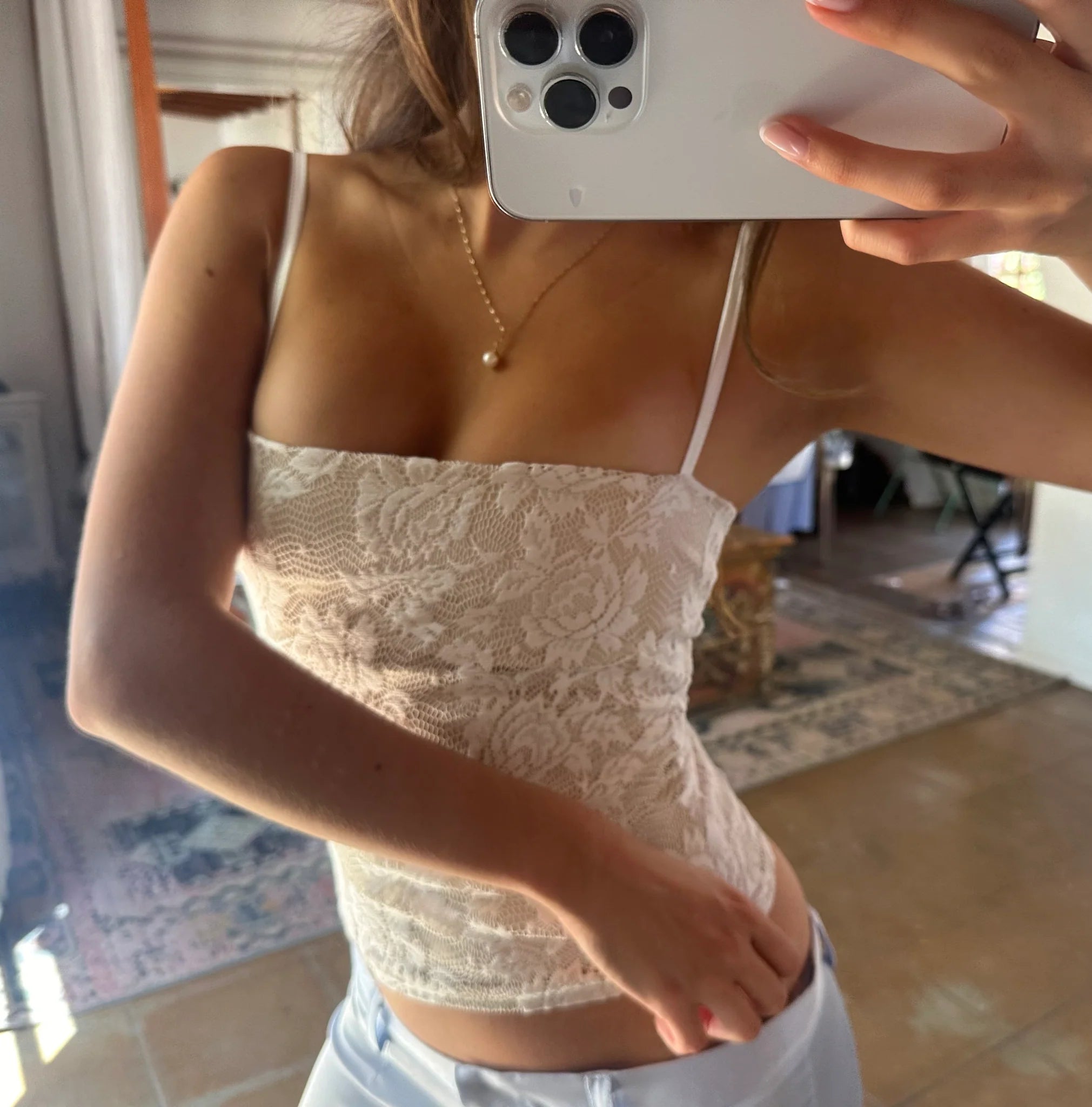 Person wearing a lace top taking a mirror selfie.