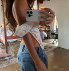 White lace off-shoulder crop top with puff sleeves paired with high-waisted blue jeans