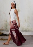 Flowing midi skirt in burgundy and dusty rose patchwork print with sheer panels and asymmetric hem.