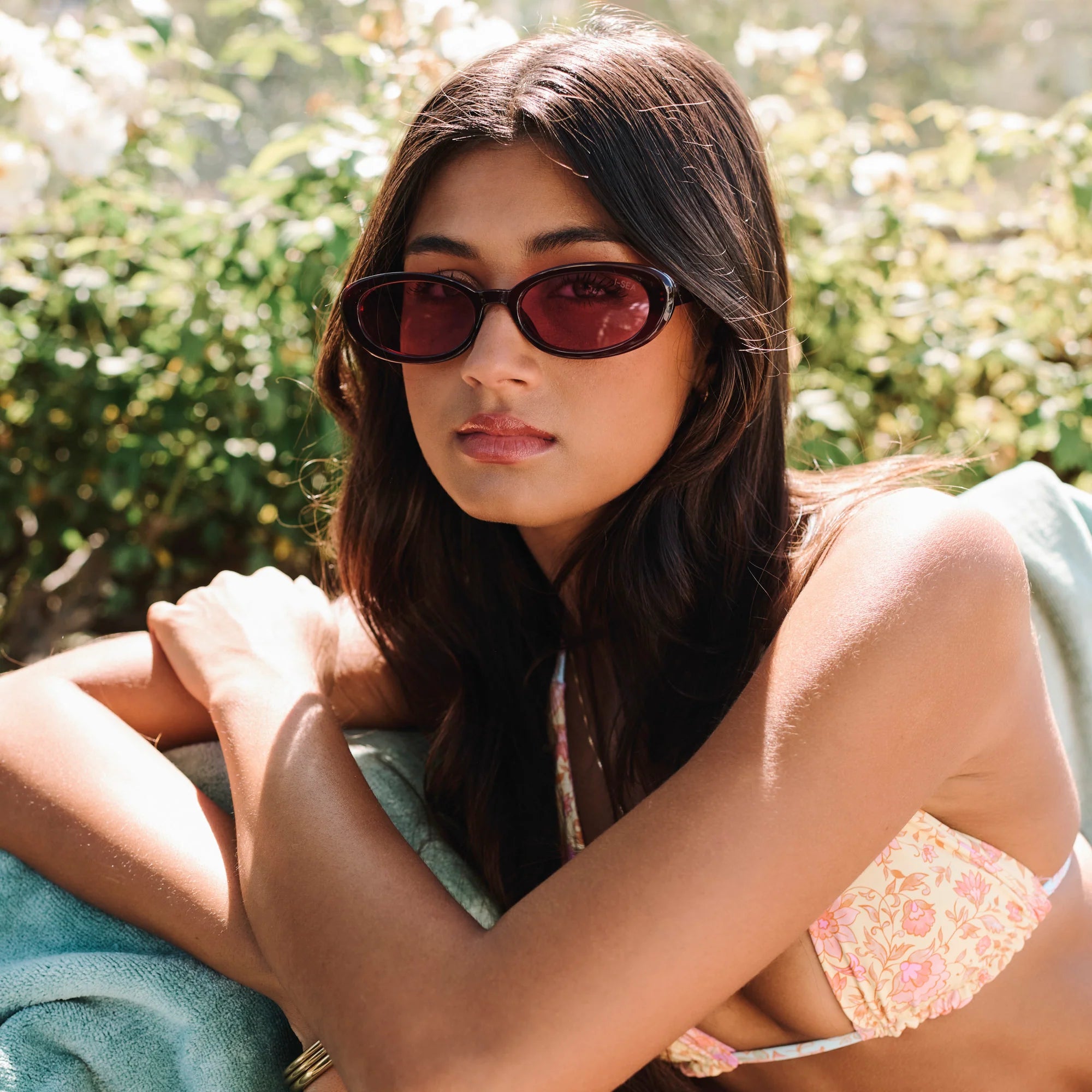 Woman wearing sunglasses and a bikini top with a blurred natural background