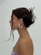 Clear acrylic claw clip holding dark brown hair in an updo, featuring transparent teeth design with chunky modern style