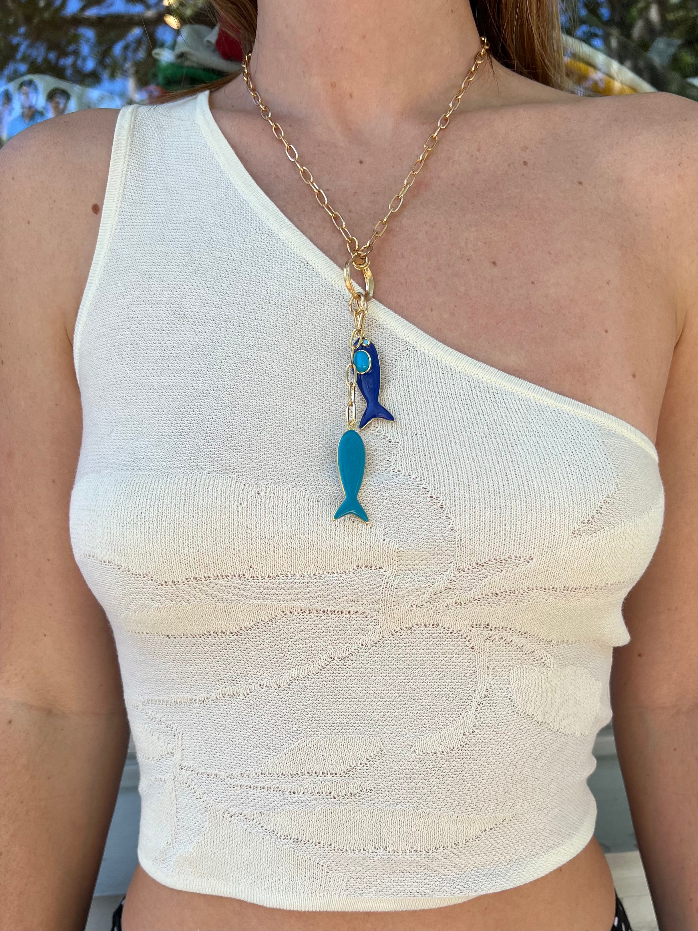 Gold chain necklace with blue enamel fish charms and lobster clasp, modeled on white ribbed tank top