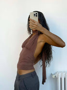 Mauve halter neck top with ruched gathering and long tie detail, worn with gray trousers