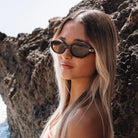 Woman wearing sunglasses against a rocky background