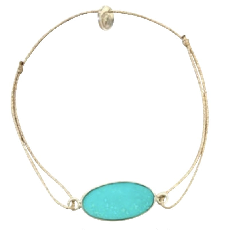 Adjustable cord bracelet with oval turquoise stone centerpiece and gold-tone accents on beige string