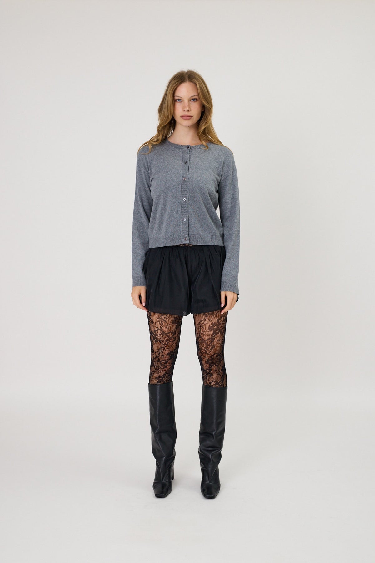 Grey button-front crew neck cardigan, fine knit, long sleeves, cropped fit, worn with black shorts and lace tights.