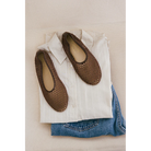 Brown woven mesh ballet flats displayed on folded white shirt and blue jeans against neutral background