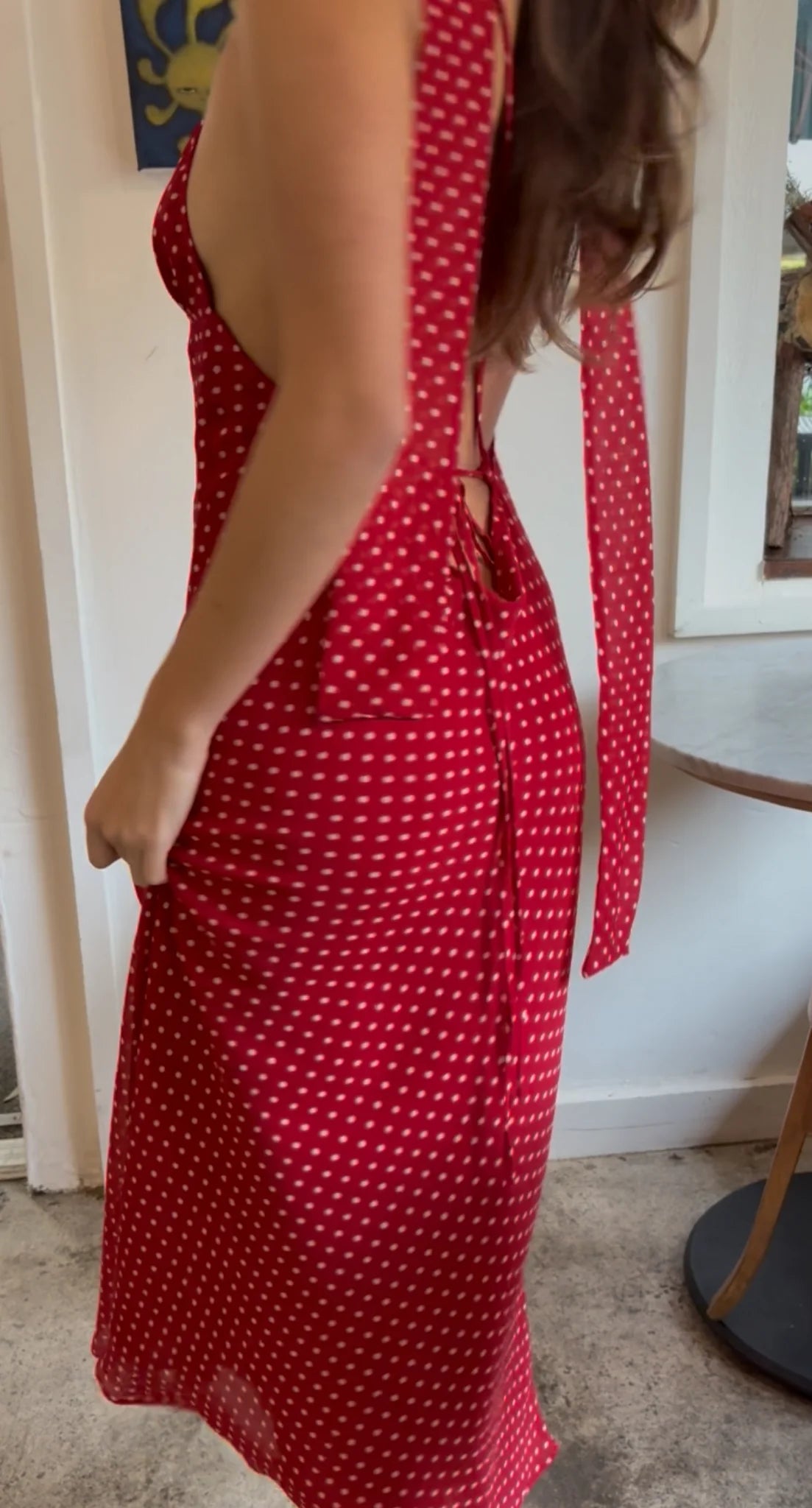 Person wearing a red polka dot dress indoors.